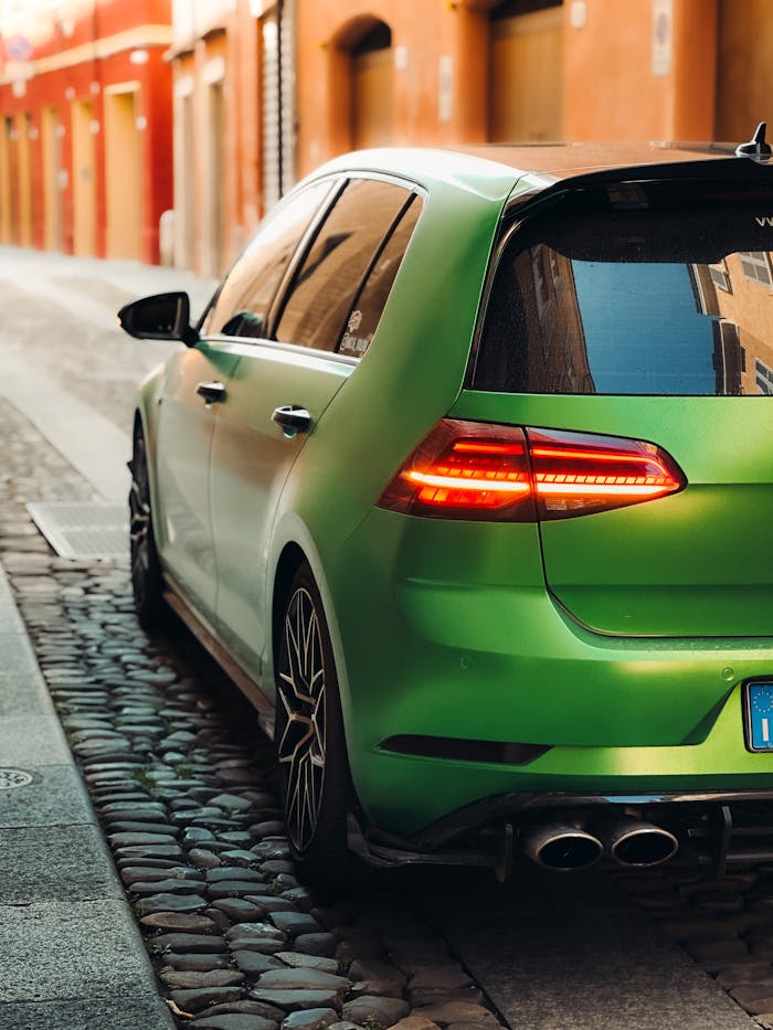 Vibrant green sport car parked in a narrow European street with cobblestone pavement.