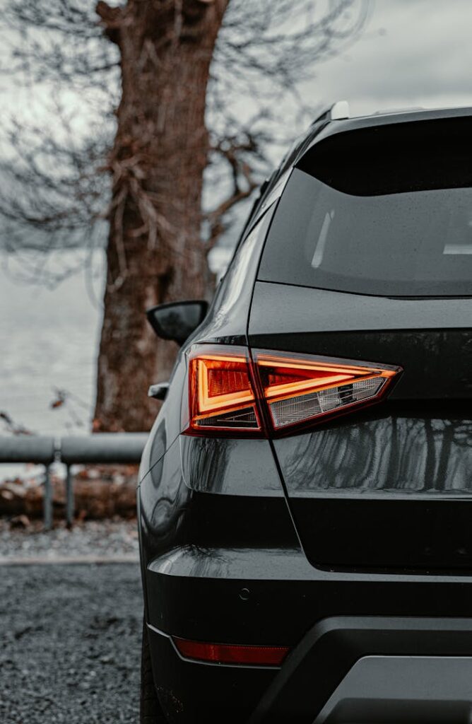 Rear view of a black car parked outdoors with autumn trees in Edinburgh, Scotland.